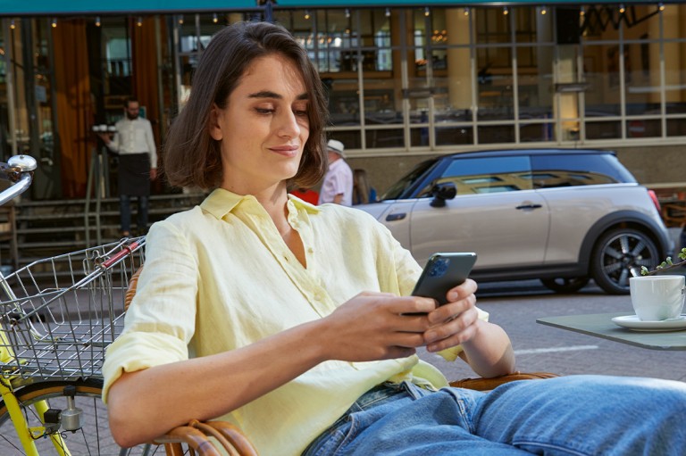 MUJER USNADO CELULAR CON UN MINI DE FONDO